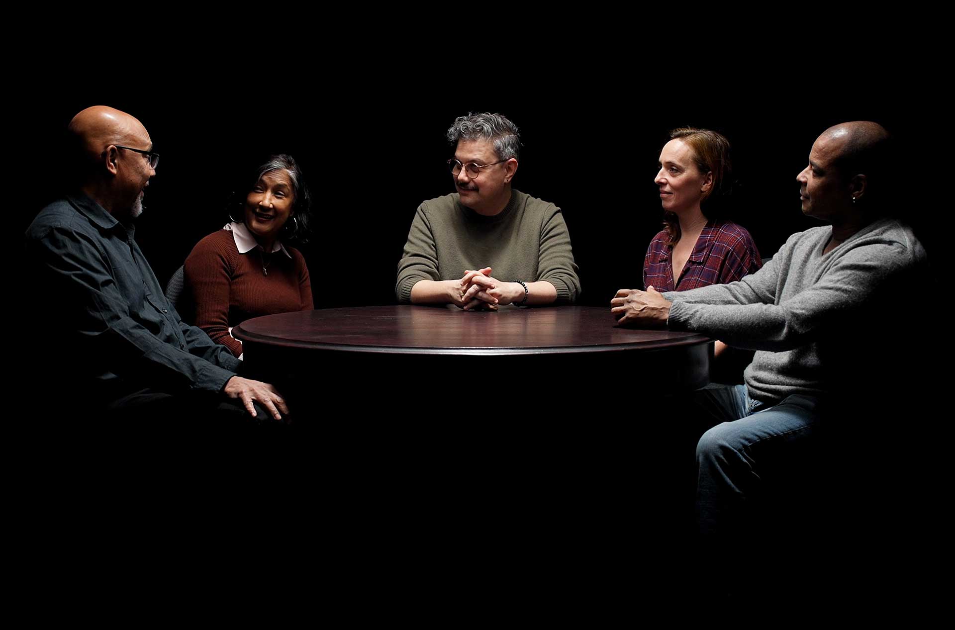 Five people sitting around a table having a discussion.